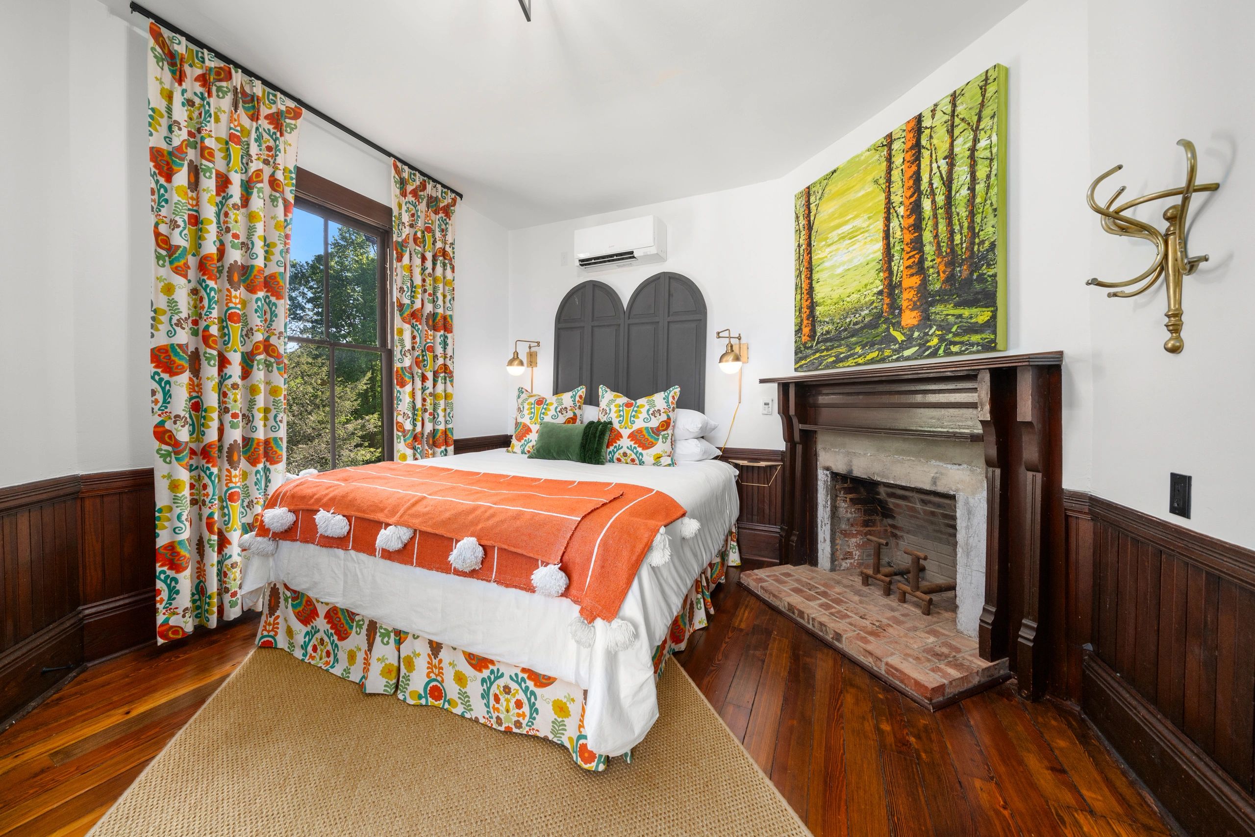 Cozy bedroom with colorful curtains, orange bedding, and a wooden fireplace